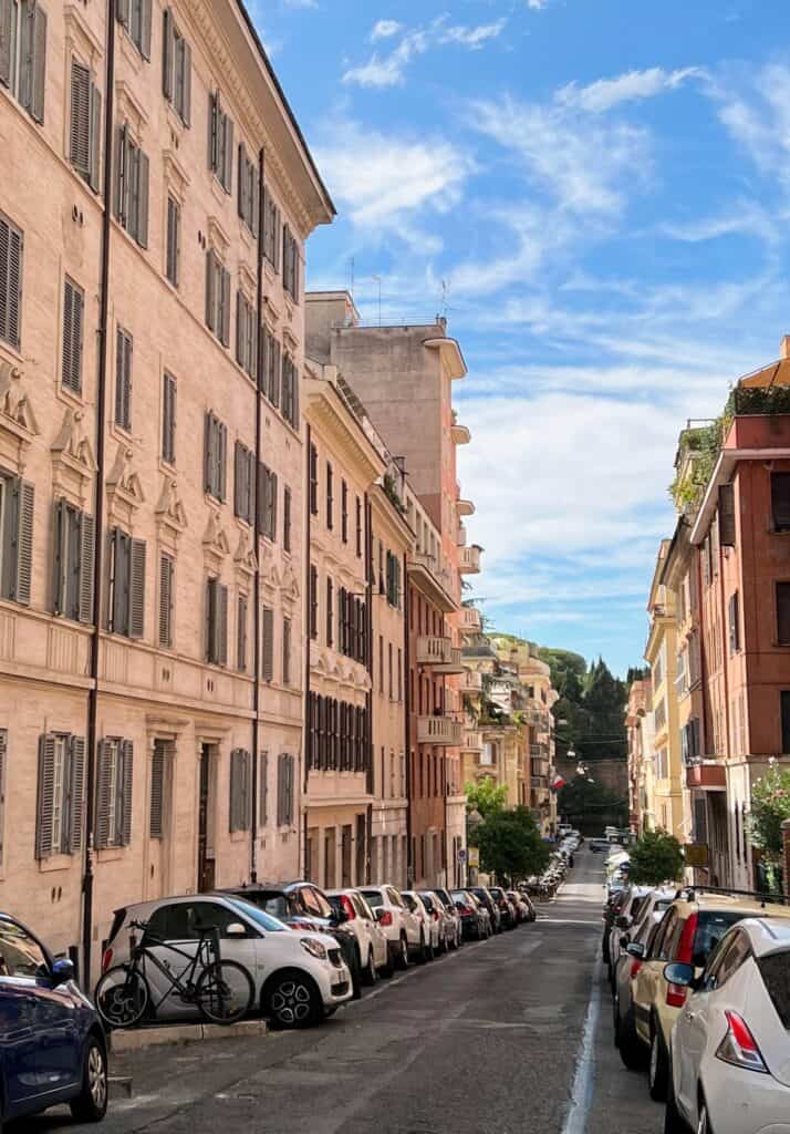 Celio Rione Neighborhood In Rome Narrow Street With Pastel Buildings And Parked Small Cars And Bike